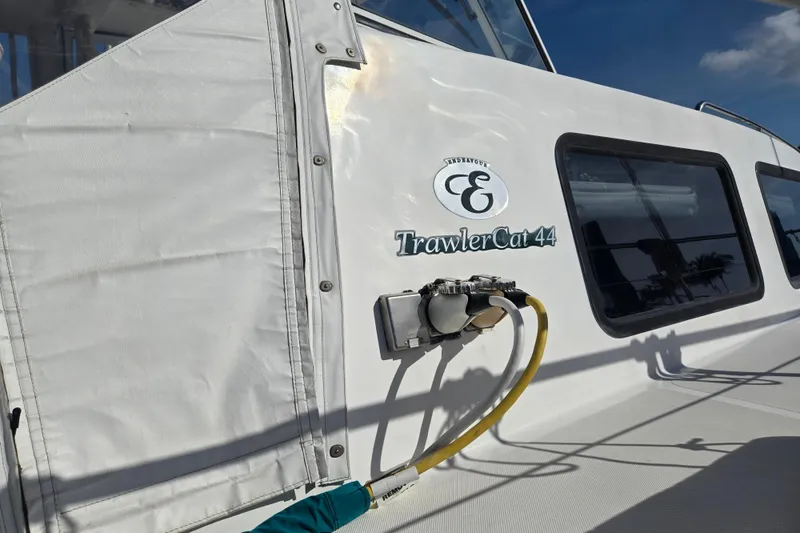 Slide: The Image of 2003 Endeavour Trawler Cat 44 boat exterior with logo and windows under clear sky. - 73