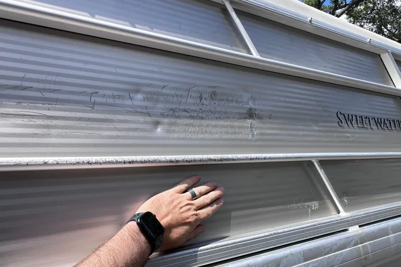 Slide: The Image of Hand inspecting scratches on 2020 Godfrey Sweetwater 2286 Tritoon boat exterior. - 26