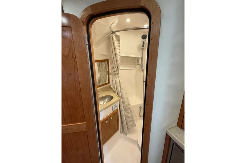 Slide: The Image of 2026 Albemarle 36 Express yacht bathroom with shower, sink, and wooden cabinetry. - 5