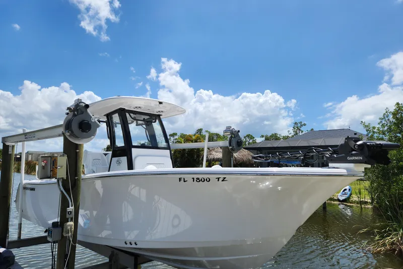 Slide: The Image of 2024 Sportsman Open 232 Center Console boat docked under a clear blue sky. - 1
