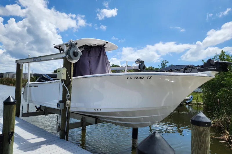 Slide: The Image of 2024 Sportsman Open 232 Center Console boat on lift, docked under blue sky. - 50