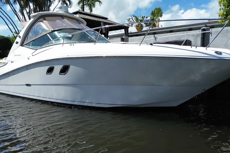 Slide: The Image of 2007 Sea Ray Sundancer 310 boat docked on calm water, under a clear blue sky. - 11