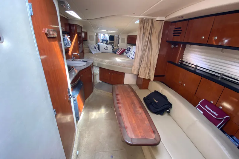 Slide: The Image of Interior of 2007 Sea Ray Sundancer 310, featuring cozy seating, wooden table, and nautical decor. - 34