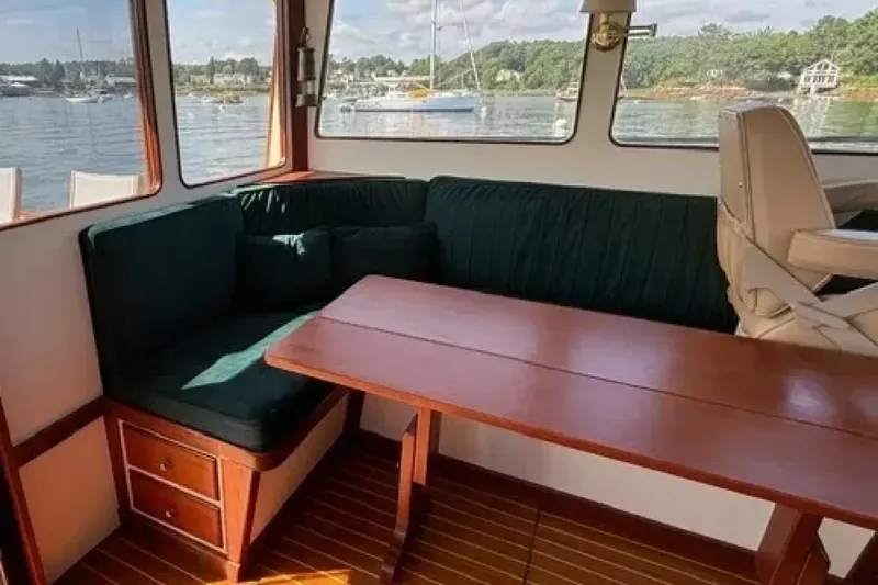 Slide: The Image of Cozy interior of 2003 Snug Harbor Shearwater boat with green seating and wooden table. - 10