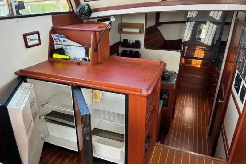 Slide: The Image of Interior of 2003 Snug Harbor Shearwater boat with open fridge and wooden cabinetry. - 13