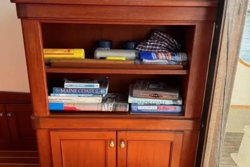 Slide: The Image of Wooden bookshelf on Snug Harbor Shearwater 2003, filled with books and nautical items. - 19