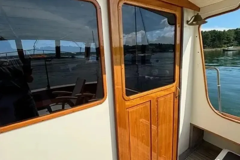 Slide: The Image of 2003 Snug Harbor Shearwater boat with wooden door and window, docked by calm waters. - 3