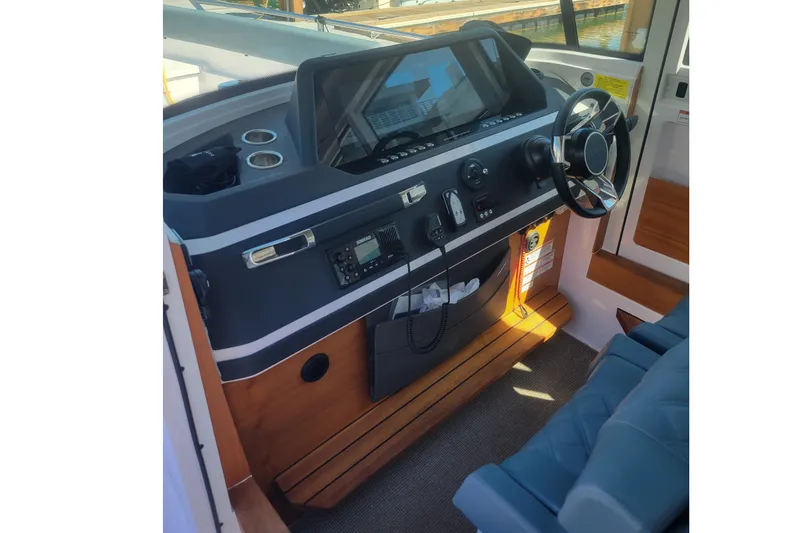 Slide: The Image of 2022 Axopar 28 Cabin helm with modern controls and steering wheel. - 3