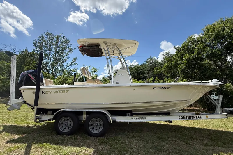 The Image of 2020 Key West 230 Bay Reef boat on trailer, parked on grass under a blue sky. - 0
