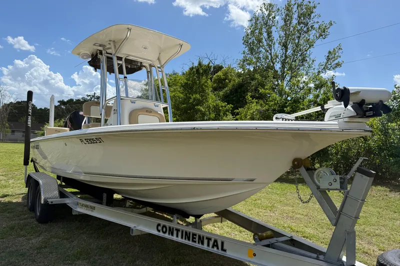 Slide: The Image of 2020 Key West 230 Bay Reef boat on trailer, parked on grass under a sunny sky. - 4
