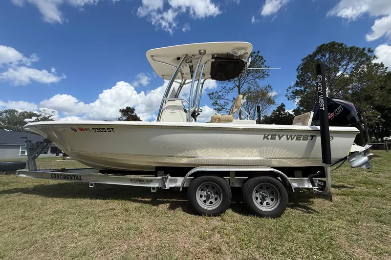 Slide: The Image of 2020 Key West 230 Bay Reef boat on trailer, parked on grass under a blue sky. - 9