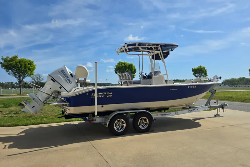 Slide: The Image of 2024 Carolina Skiff 24 Ultra Elite boat on trailer, parked outdoors under blue sky. - 11