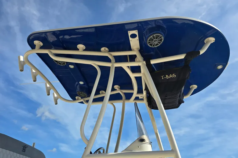 Slide: The Image of 2024 Carolina Skiff 24 Ultra Elite T-top with rod holders against blue sky. - 19