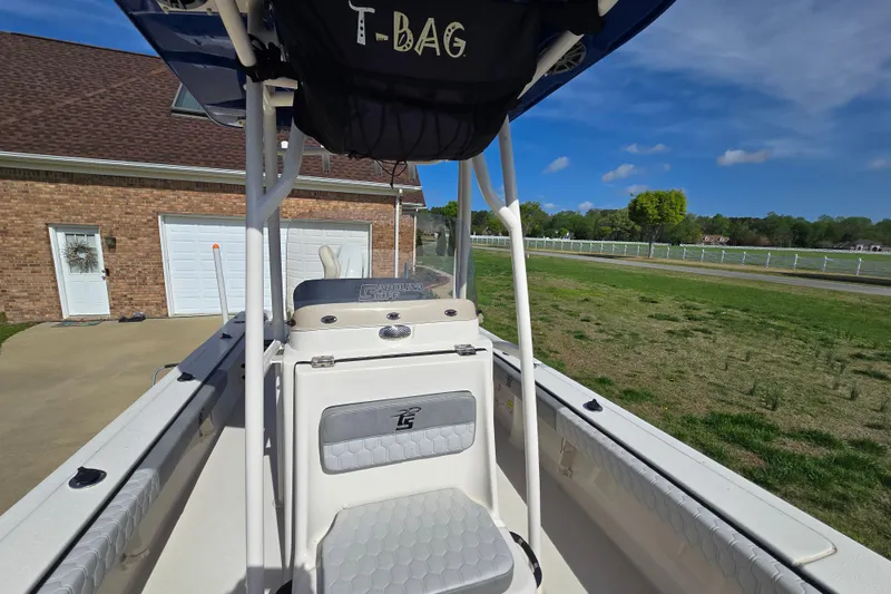 Slide: The Image of 2024 Carolina Skiff 24 Ultra Elite boat parked near a brick house under a clear blue sky. - 38