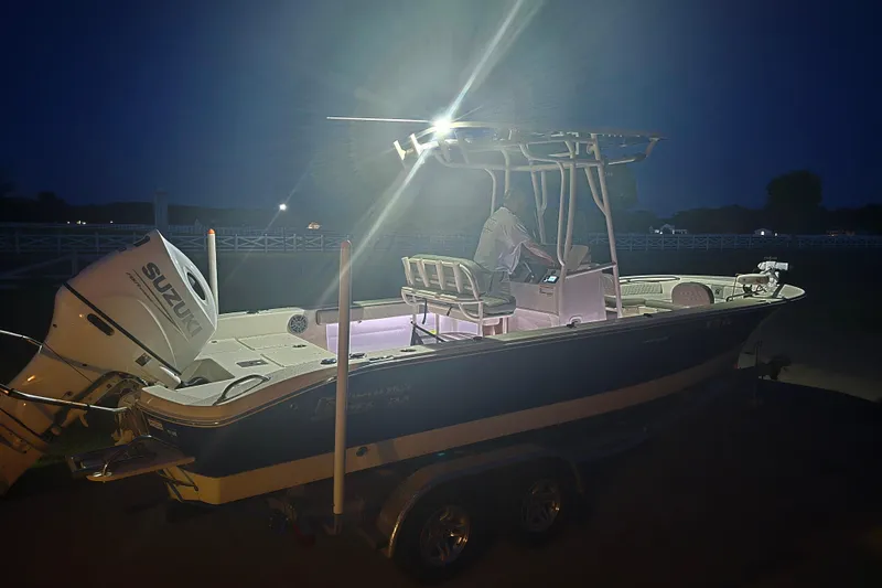Slide: The Image of 2024 Carolina Skiff 24 Ultra Elite boat illuminated at night, featuring a Suzuki outboard motor. - 43