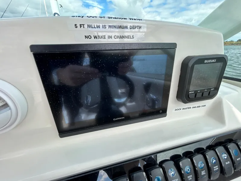 Slide: The Image of 2024 Sailfish 226 DC dashboard with Garmin and Suzuki displays, depth warning sign. - 26