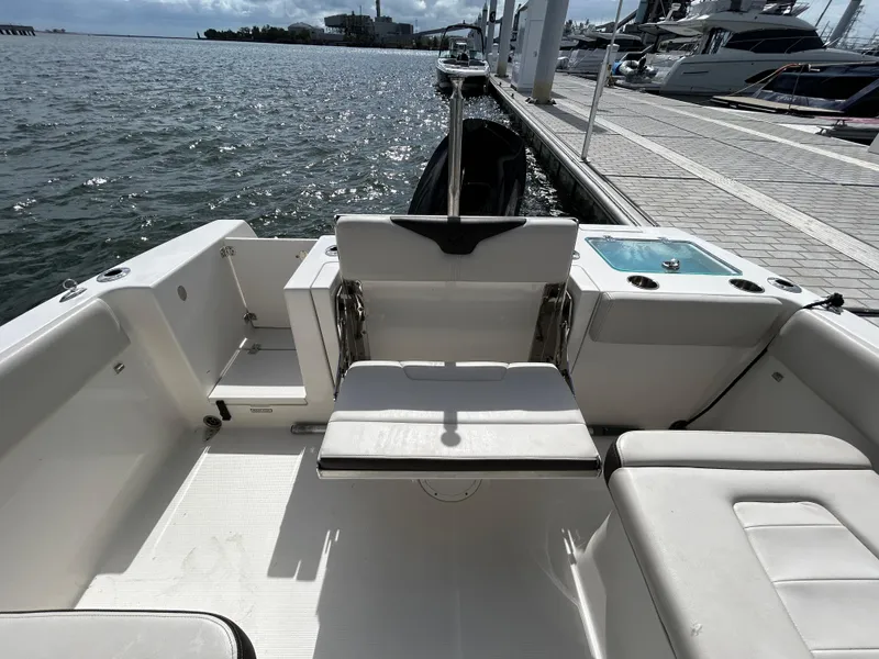 Slide: The Image of 2024 Sailfish 226 DC boat interior with seating, docked by the water. - 6