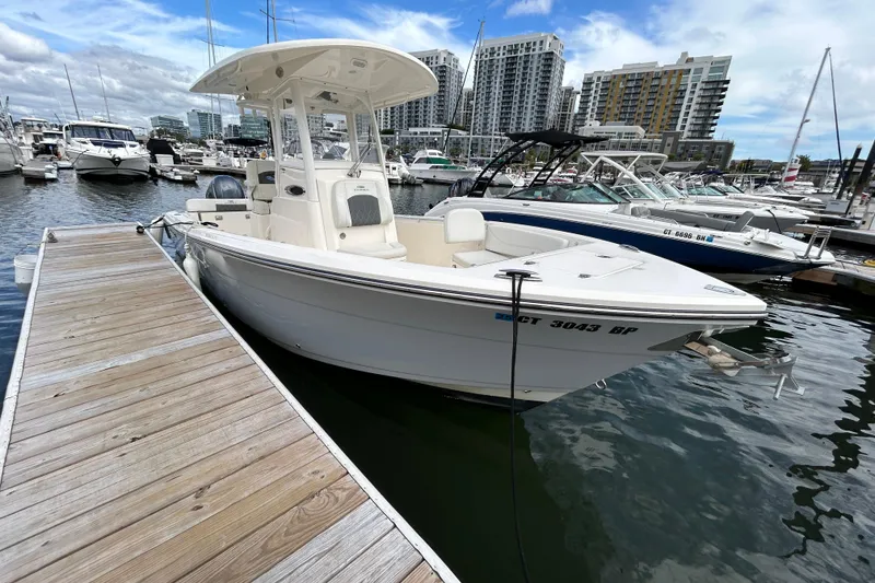 The Image of 2023 Cobia 240 Center Console boat docked at marina with city skyline. - 1