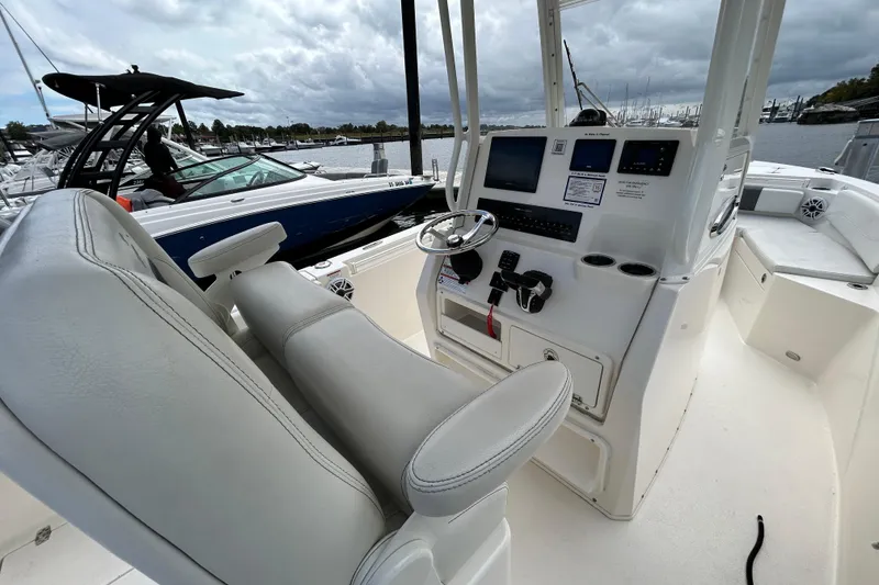 Slide: The Image of 2023 Cobia 240 Center Console boat interior with helm and seating, docked at marina. - 12