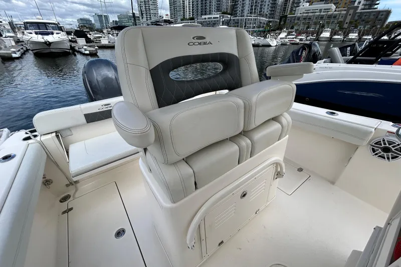 Slide: The Image of 2023 Cobia 240 Center Console boat interior with luxurious seating at marina. - 13