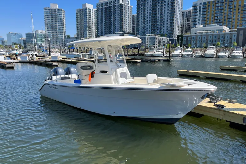 Slide: The Image of 2023 Cobia 240 Center Console boat docked in urban marina with city skyline. - 14