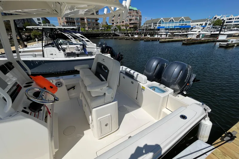 Slide: The Image of 2023 Cobia 240 Center Console boat docked, featuring dual Yamaha engines and modern interior. - 18