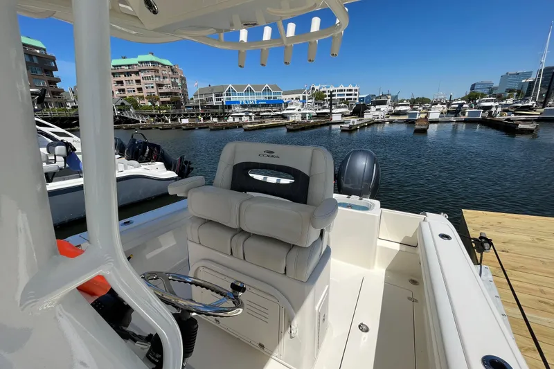 Slide: The Image of 2023 Cobia 240 Center Console boat docked at a marina with waterfront buildings. - 20
