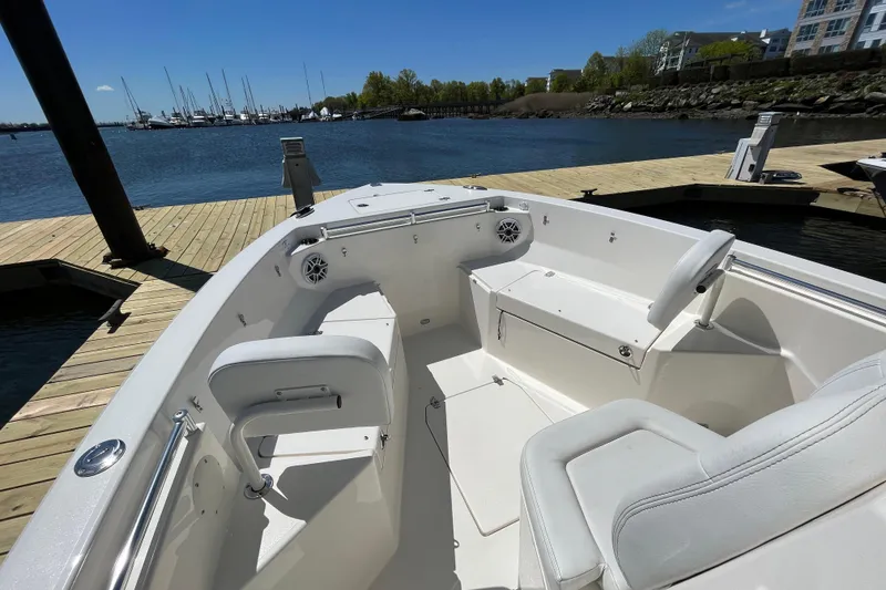 Slide: The Image of 2023 Cobia 240 Center Console boat interior at dock, featuring white seating and waterfront view. - 21