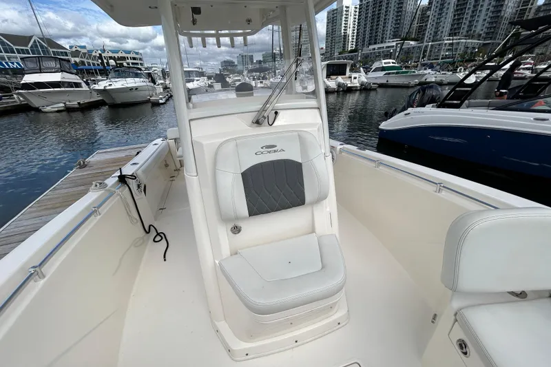 Slide: The Image of 2023 Cobia 240 Center Console boat docked in a marina with cityscape background. - 26