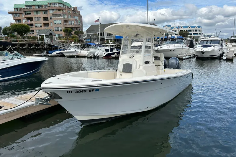 Slide: The Image of 2023 Cobia 240 Center Console boat docked in a marina with other vessels. - 3