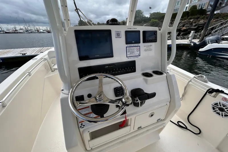Slide: The Image of 2023 Cobia 240 Center Console boat helm with steering wheel and navigation screens. - 9