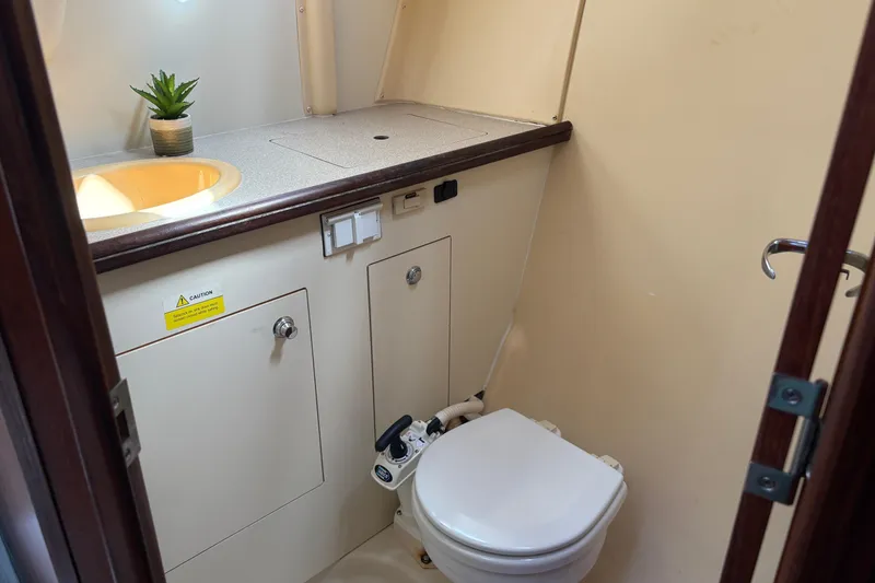 Slide: The Image of Compact bathroom in a 2006 Hunter 31 sailboat, featuring a toilet and sink. - 8