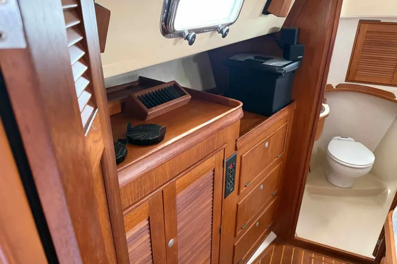 Slide: The Image of Interior of a 1998 Island Packet 40 sailboat, featuring wooden cabinetry and a compact bathroom. - 12