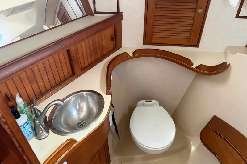 Slide: The Image of 1998 Island Packet 40 yacht bathroom with wooden cabinetry, stainless steel sink, and toilet. - 13