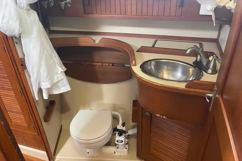 Slide: The Image of 1998 Island Packet 40 yacht bathroom with wooden cabinetry, sink, and marine toilet. - 28