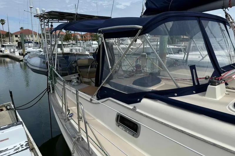 Slide: The Image of 1998 Island Packet 40 sailboat docked at marina, featuring blue canopy and polished deck. - 40