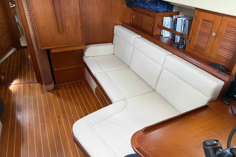 Slide: The Image of Interior of 1998 Island Packet 40 sailboat with white cushioned seating and wooden cabinetry. - 6