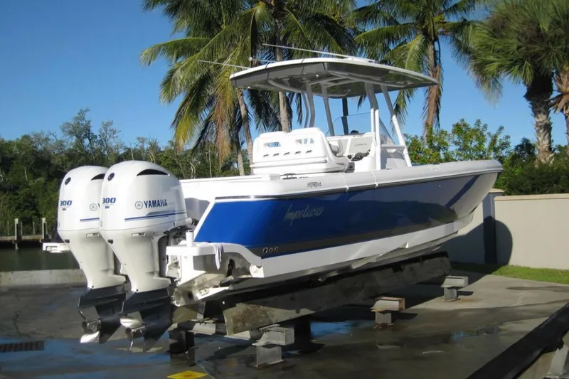 Slide: The Image of 2020 Intrepid 327 Center Console boat with twin Yamaha engines, docked near palm trees. - 2