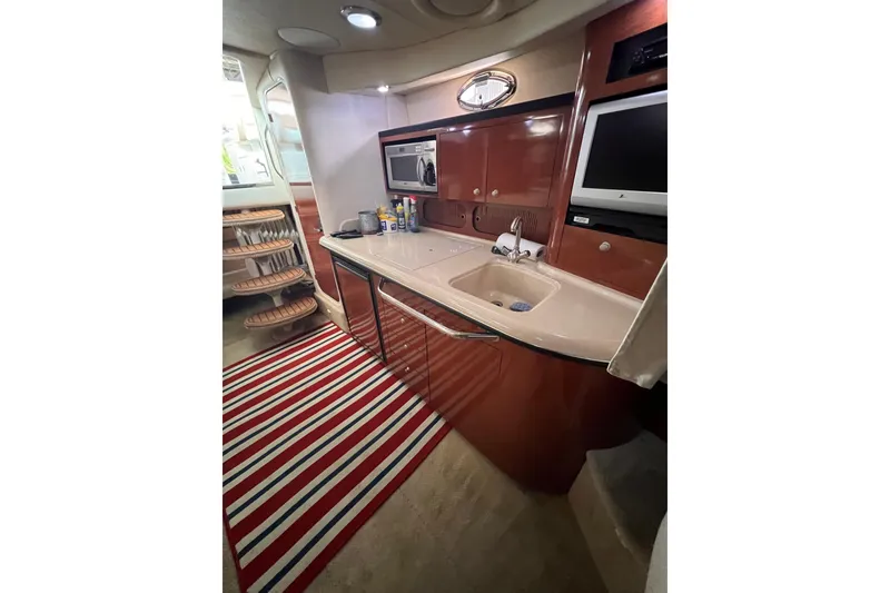 Slide: The Image of 2005 Sea Ray 340 Sundancer interior kitchen with sink, microwave, and striped rug. - 2