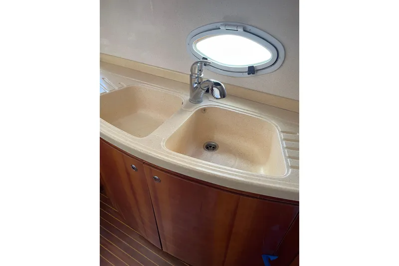 Slide: The Image of Kitchen sink area on 2000 Azimut 46 Flybridge MY yacht, featuring dual basins and a porthole. - 46