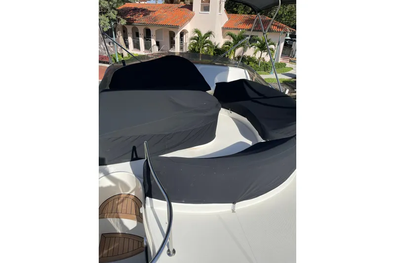 Slide: The Image of Flybridge of 2000 Azimut 46 yacht with black covers, docked near a house. - 83