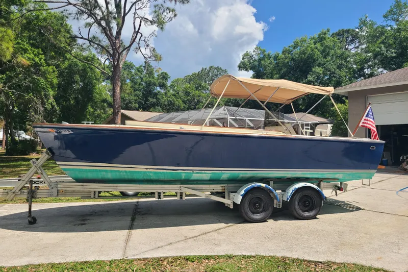 The Image of 1964 Holmes 25 Cuddy boat on trailer, navy and teal, with canopy and American flag. - 0