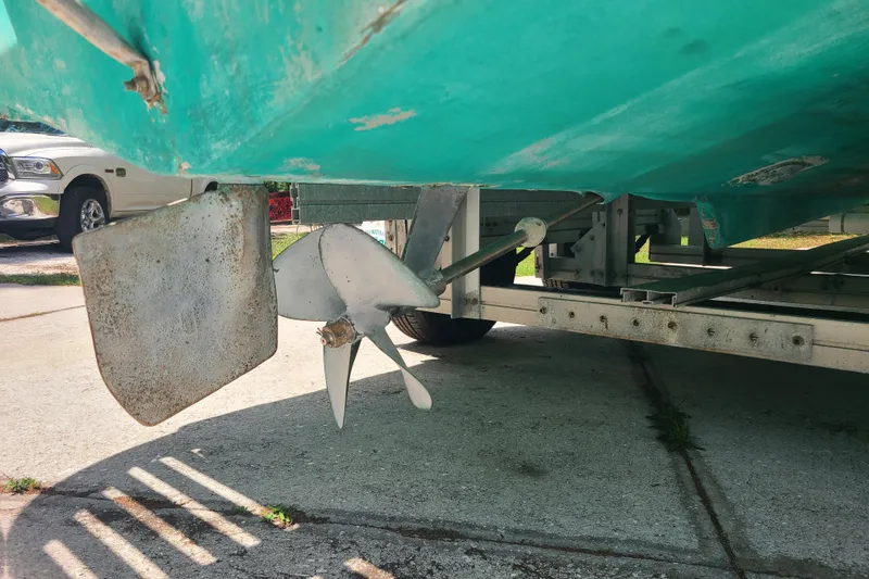 Slide: The Image of 1964 Holmes 25 Cuddy boat propeller and rudder on trailer, parked outdoors. - 28