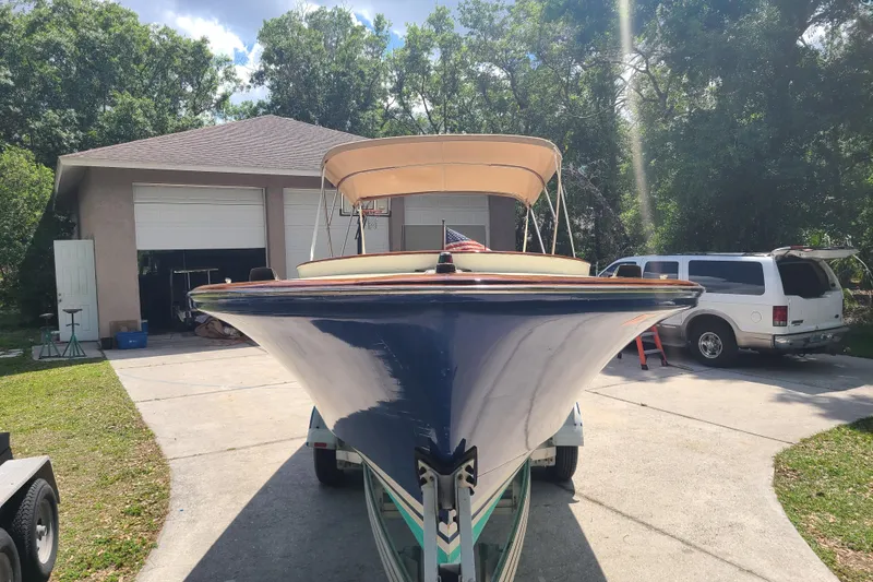 Slide: The Image of 1964 Holmes 25 Cuddy boat on trailer, parked in driveway near garage and vehicles. - 4