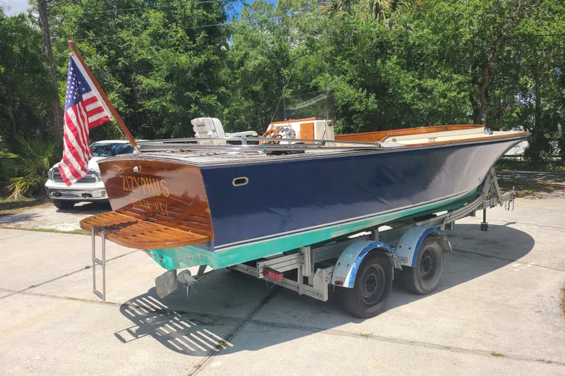 Slide: The Image of 1964 Holmes 25 Cuddy boat on trailer with American flag, parked outdoors. - 5
