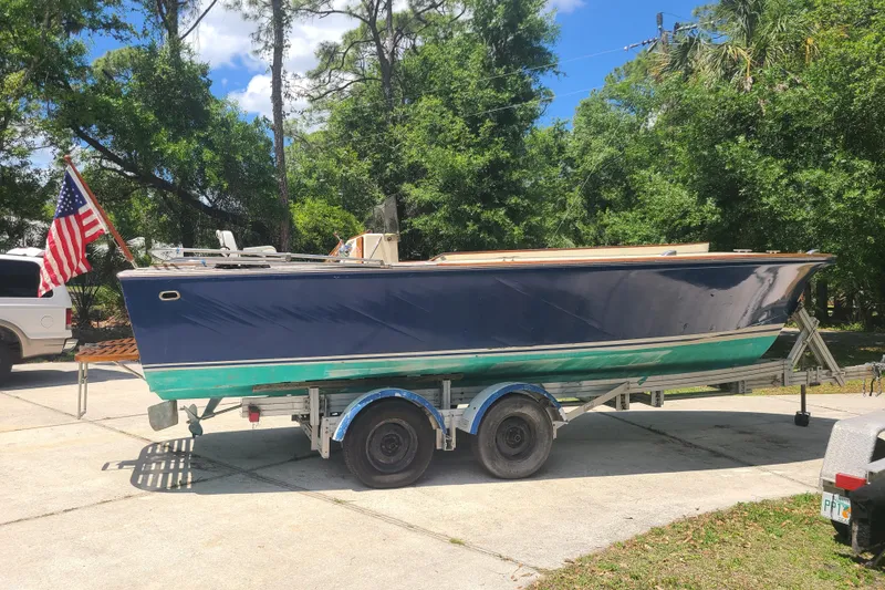 Slide: The Image of 1964 Holmes 25 Cuddy boat on trailer with American flag, parked outdoors. - 6