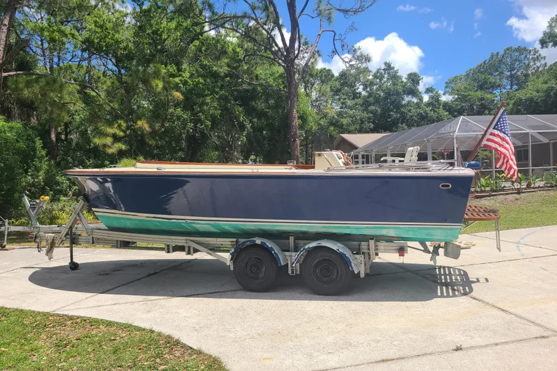 Slide: The Image of 1964 Holmes 25 Cuddy boat on trailer, parked outdoors with American flag. - 7