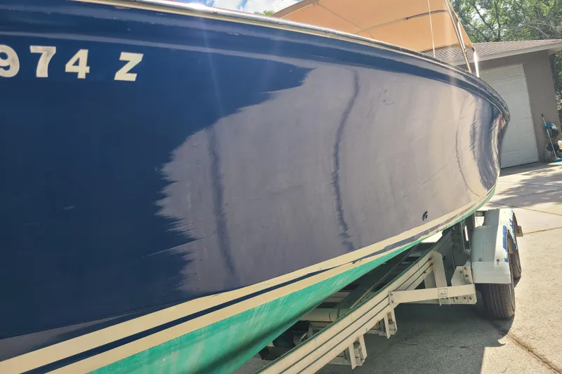 Slide: The Image of 1964 Holmes 25 Cuddy boat on trailer, blue hull, partial paintwork visible. - 8