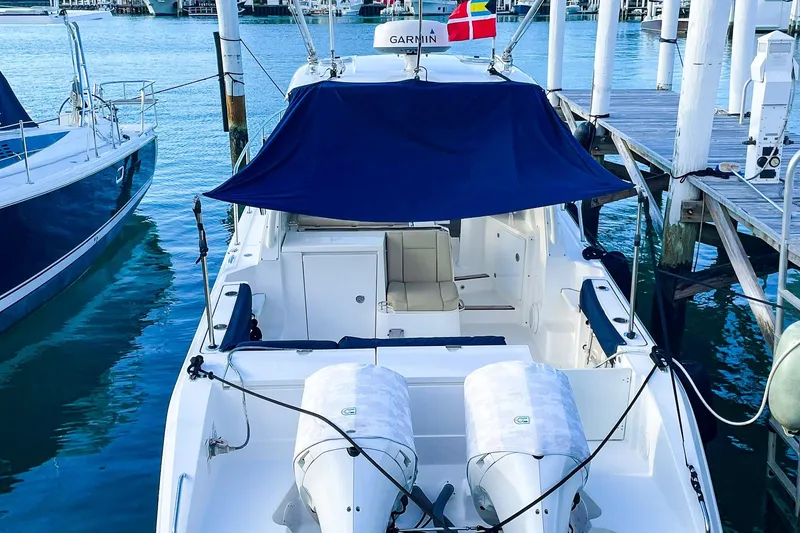 Slide: The Image of 2020 Pursuit OS 325 Offshore boat docked, featuring dual engines and a blue canopy. - 11