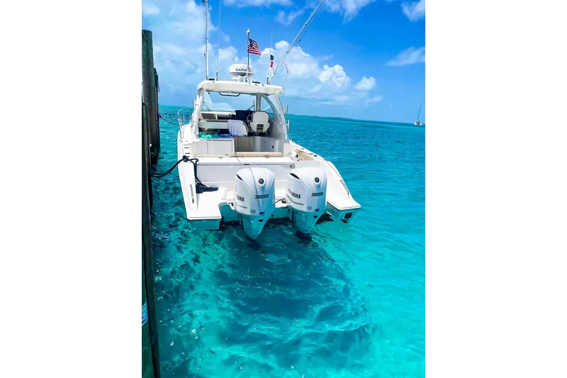 Slide: The Image of 2020 Pursuit OS 325 Offshore boat docked in clear turquoise water under a bright blue sky. - 14